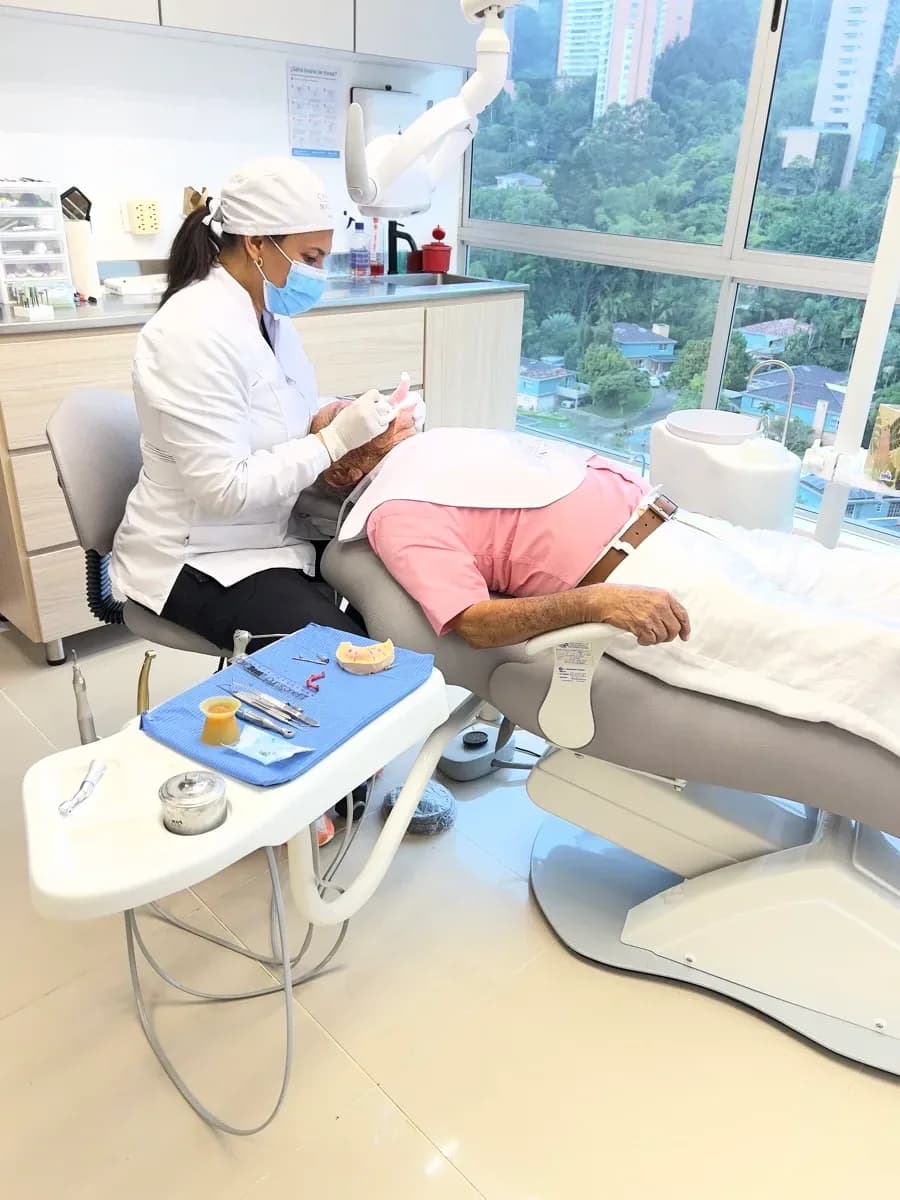 Dra. Carolina Macareno atendiendo a un paciente en su consultorio de Medellín con vista a la ciudad